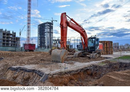 Excavator During Earthmoving At Construction Site On Bluue Sky Background. Onstruction Machinery For