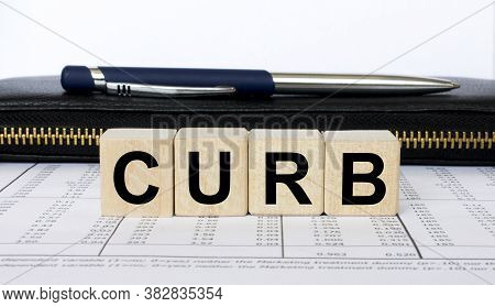 A Word Curb Written In A Wooden Cube With A Pen And Wallet