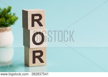 Ror - Rate Of Return. Wooden Blocks With The Word Ror, Blue Background.