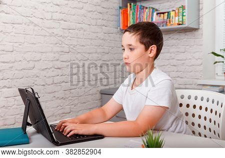Preteen Schoolboyl Using Gadgets To Study. Toddler Boy Doing Her Homework With Laptop At Home. Educa