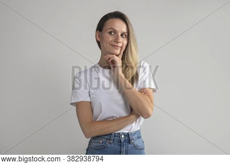 Woman With Blonde Hair Looking Aside Holding Hand Under Chin Indenting To Realize Tricky Plan. Attra