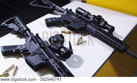 Tactical Rifle With A Colimator Sight And Some Ammunition On The Table.