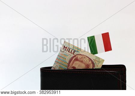 One Thousand Lire Of Italy Banknote And Mini Italia Nation Flag Stick On The Black Wallet With White