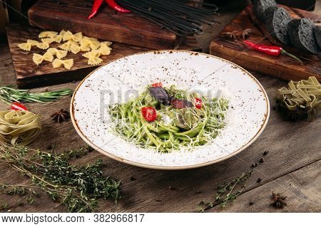 Italian Green Spaghetti Pasta With Tomatoes And Cheese On The Decorated Wooden Table