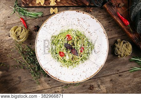 Top View On Italian Green Spaghetti Pasta With Tomatoes And Cheese On The Decorated Wooden Table