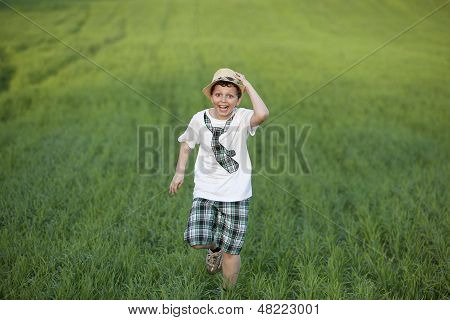 Happy boy is running on green field