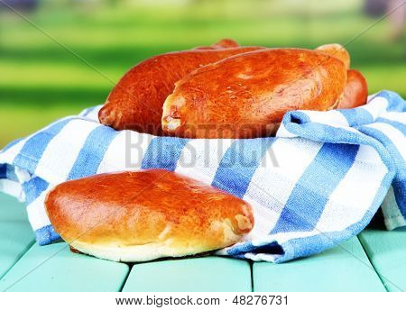 Empanadillas al horno frescos, en mesa de madera, sobre fondo brillante