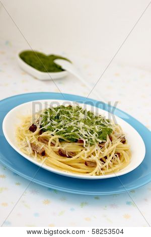 Italian pasta with pesto sauce on a blue plate.