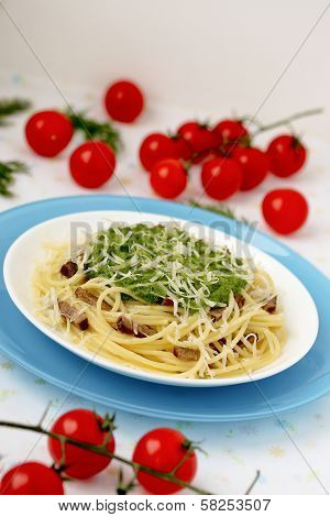 Italian pasta with pesto sauce on a blue plate.