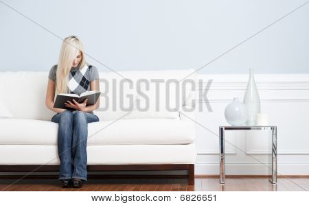Donna seduta sul divano e leggendo il libro
