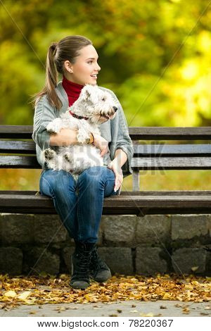 Young woman with a maltese dog sitting in park 