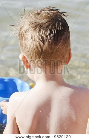 back of a baby boy playing by the sea
