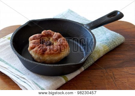 dumpling with meat lies in a cast iron pan standing on a wooden cutting Board