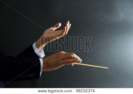 Music conductor hands with baton on black background