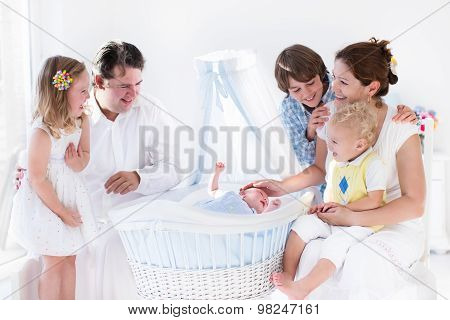 Family Playing With Newborn Child In White Bassinet