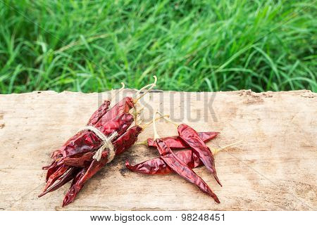 Dried Chili Peppers On Wooden With Green Grass Background