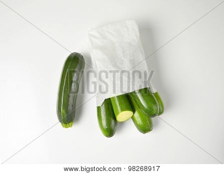 bag of baby courgettes on white background