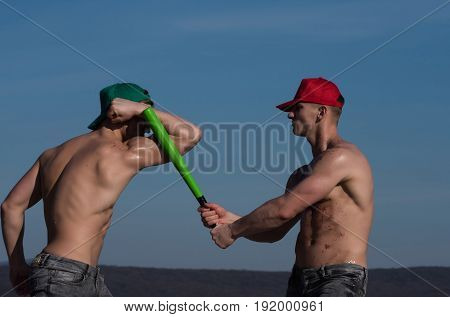 men baseball player with green bat on sunny blue sky background
