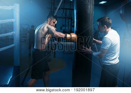 Man in black handwraps exercises with bag in gym