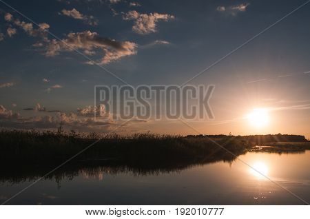 The setting sun over the water, sunset on the waterfront, the dramatic sky