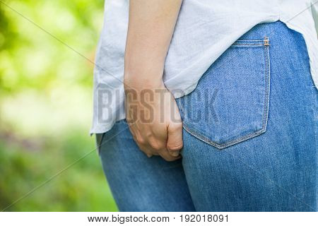 Close up picture of a young woman holding her butt she needs to poop outdoor