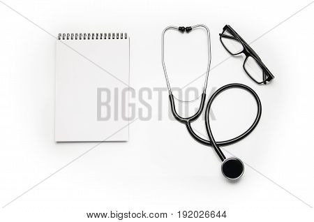 Stethoscope and prescription notepad isolated on white background. Sterile doctors office desk. Medical accessories on a white table background with copy space around products. Photo taken from above.