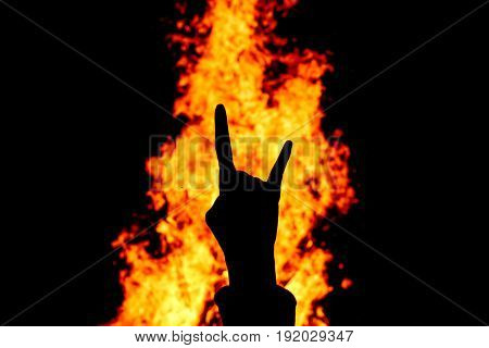 Silhouette of Rock and Roll hand sign against the fire background.