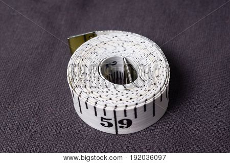 Inch, Centimeter Tape On A Background Of Grey Fabric