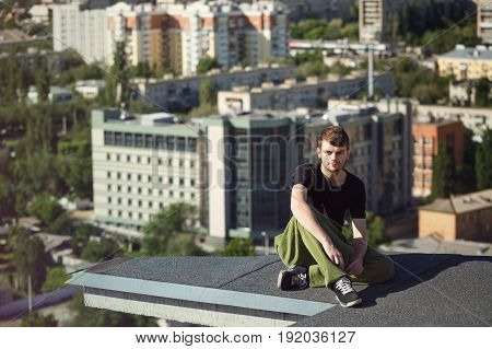 The roofer rests after climbing to the roof. Active way of life in urban space. Courage and adrenaline.
