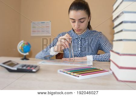 Young Girl is working with atlas at the wood table. Education and school concept