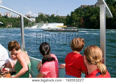 People In A Tourist Boat Approaching The Rhine Waterfalls