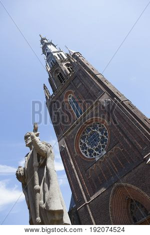 boniface church with statue and blue sky in leeuwarden capital of friesland on sunny summer day seen through trees
