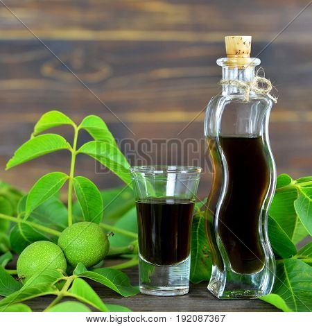 Close up of green walnut liqueur on wooden background