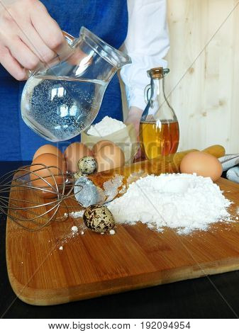 Ingredients for dough kneading. A baker is standing in the background