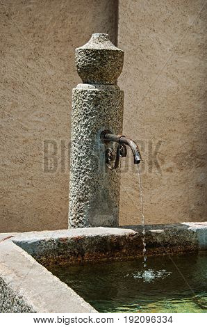 Close up of stone fountain in Megève, French Alps, alpine landscape, blue sky with clouds