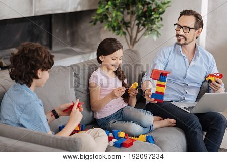 Enjoyable game. Lovely single-parent family sitting on the sofa and assembling a colorful erector set, seemingly having a great time together