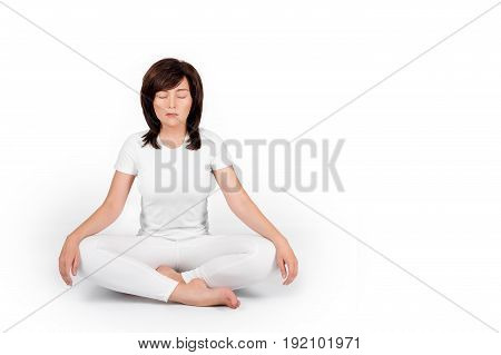 Woman practicing yoga on white background. Girl wearing white meditating with closed eyes, sitting in lotus position or in padmasana exercise