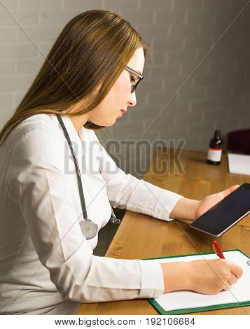 Smiling doctor using a tablet computer in a hospital.