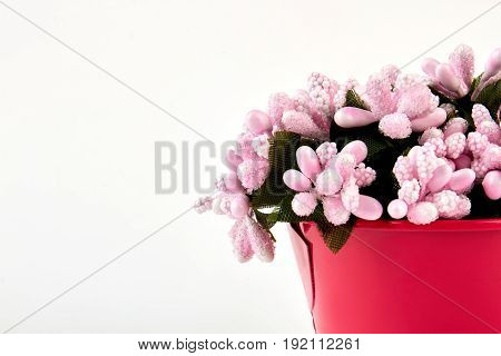 Closeup bouquet of artificial flowers. Ornamental bouquet in red bucket on white background. Vintage bloom decoration.