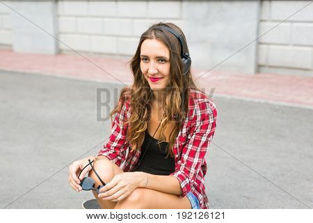 Young smiling woman relaxing and listening to music with headphones in the street