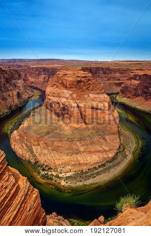 Vertical image of Horseshoe Bend near Page Arizona. It is a sandstone rock formation surrounded by the Colorado River. The color is bright and vivid.