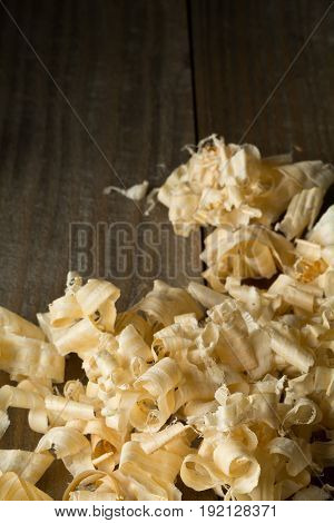 Light brown wood shavings from carpenter's hand planer or chisel work on wooden boards background with copy space