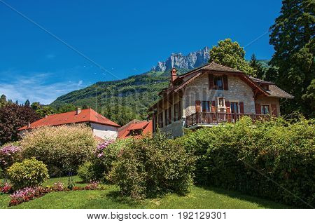 View of houses in the village of Talloires, next to the Lake of Annecy. Mountains landscape and blue sky on background. France