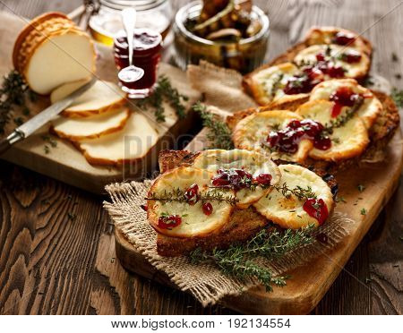 Grilled sandwich  with smoked sheep cheese, thyme  and wild red huckleberry jam on a wooden rustic table