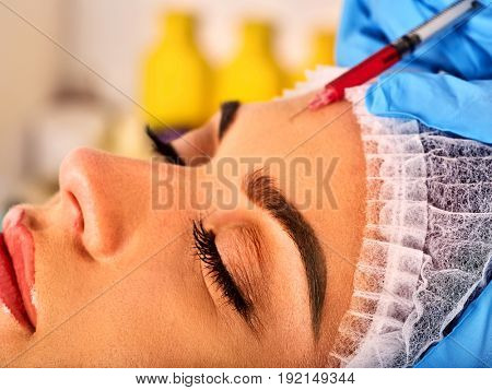 Filler injection for female forehead face. Plastic aesthetic facial surgery in beauty clinic. Cosmetic procedure. Doctor in medical gloves with syringe injects removal of forehead wrinkles .