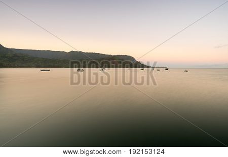 Sunrise lights the dawn sky above Hanalei Bay with the Na Pali coast in the background near Hanalei, Kauai, Hawaii