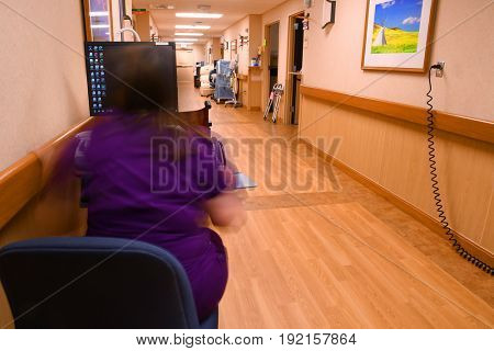 UNITED STATES - June 19, 2017: Nurse in motion working at her computer station at a hospital