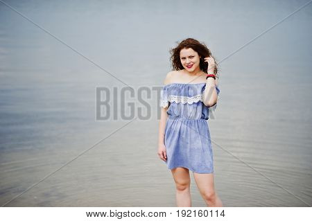 Portrait Of A Beautiful Girl With Curly Hair Wearing Marine Blye Dress Stands In The Water.
