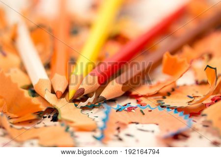 Colored pencils among chips at a white background close-up
