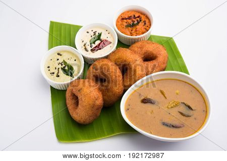 south indian food called vada sambar or sambar vada or wada, served with coconut, green and red chutney over fresg banana leaf, selective focus